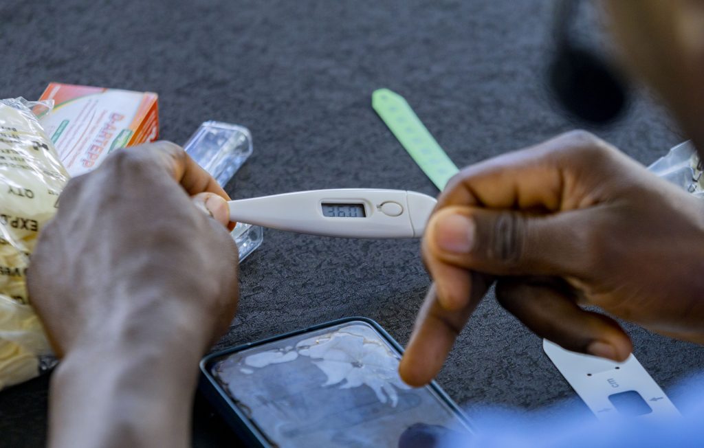Un agent de santé communautaire contrôle la température d'un bébé lors de la cérémonie de lancement du projet
