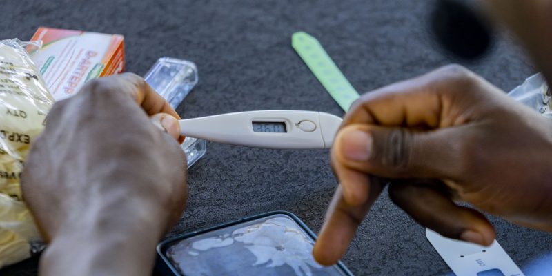 Un agent de santé communautaire contrôle la température d'un bébé lors de la cérémonie de lancement du projet