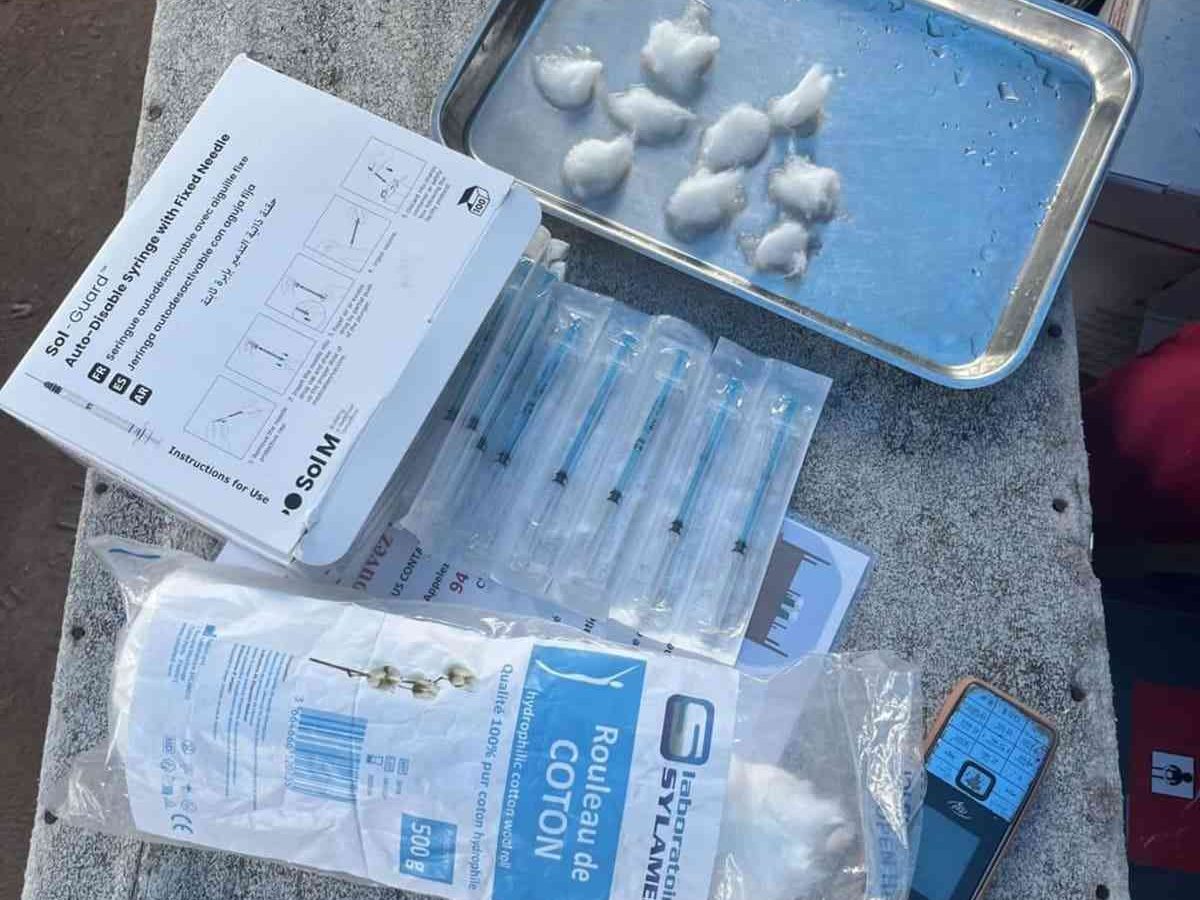 Medical injection kit preparation with safety syringes and cotton swabs.