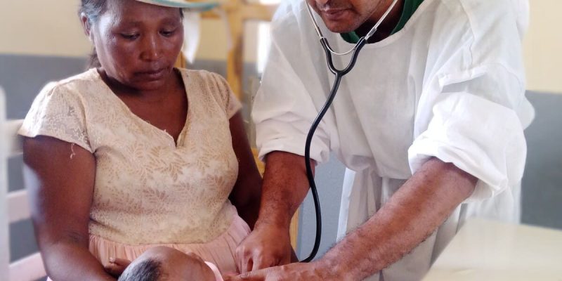 Un médecin examinant avec un stéthoscope un bébé tenu par sa mère