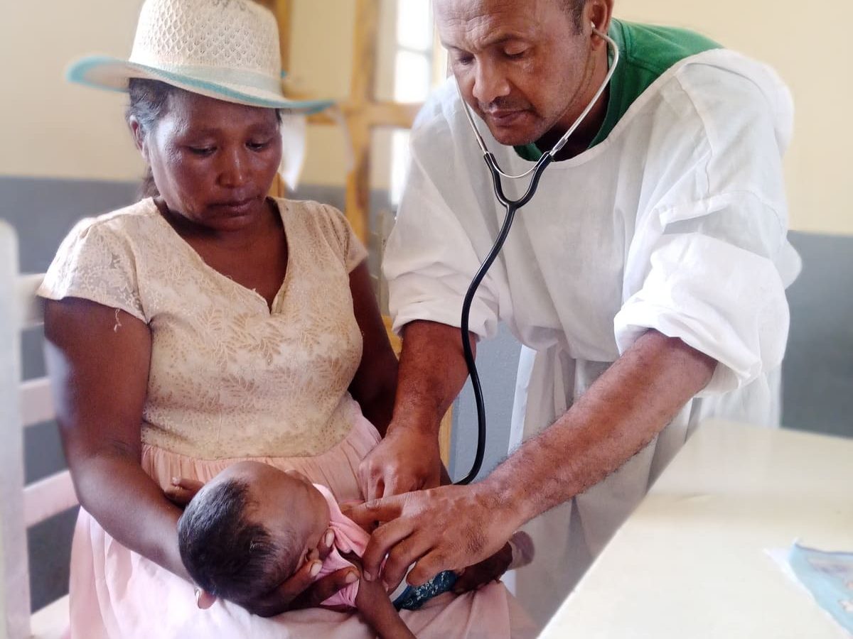 Un médecin examinant avec un stéthoscope un bébé tenu par sa mère