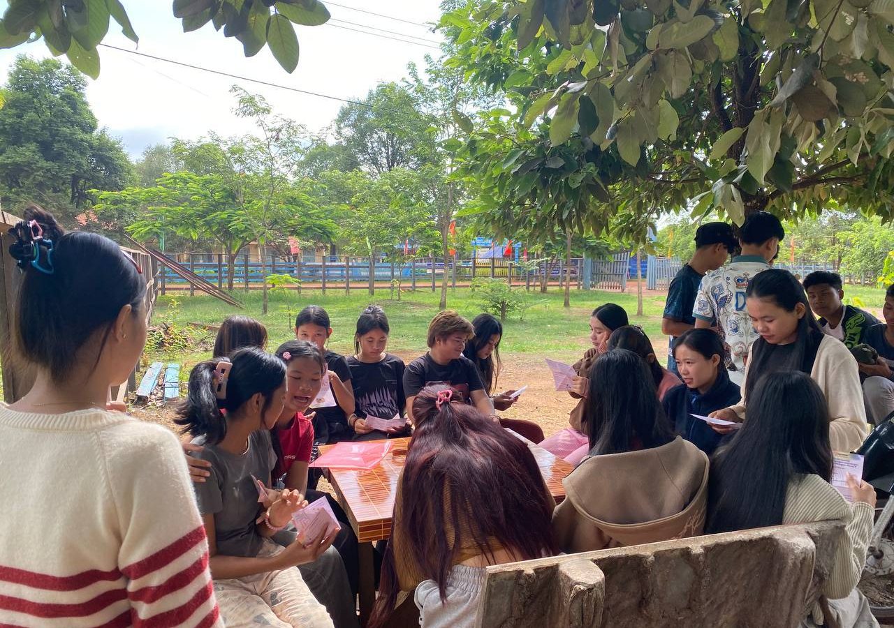 A Group Of Young People Reading Psea Leaflet Produced By The Regenerate Cambodia