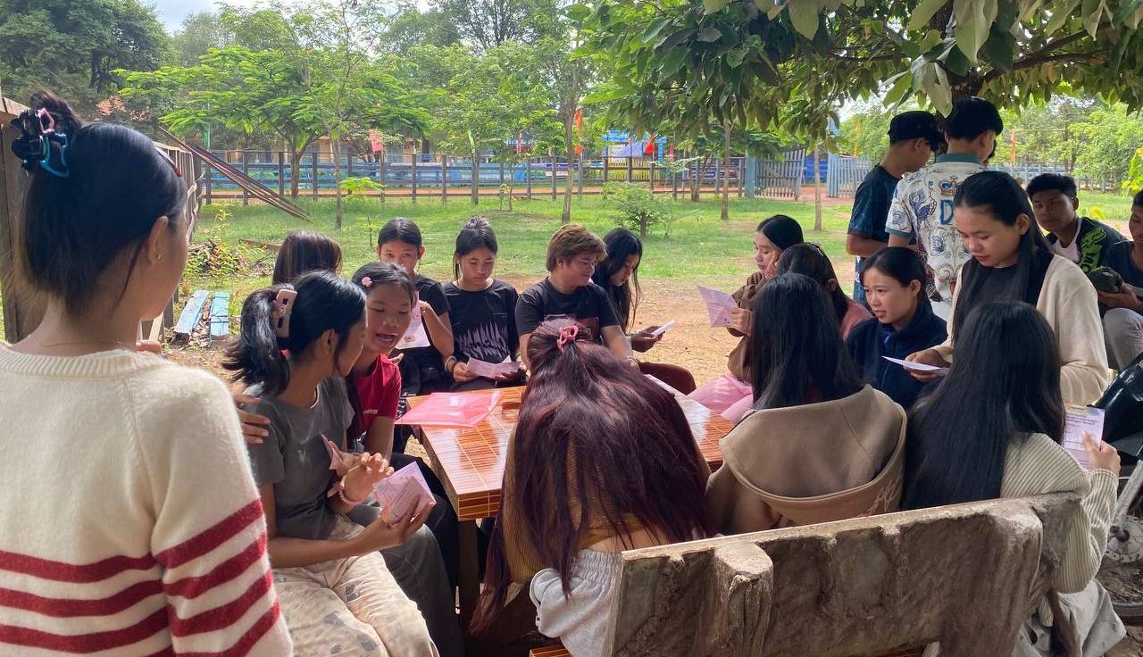 A Group Of Young People Reading Psea Leaflet Produced By The Regenerate Cambodia